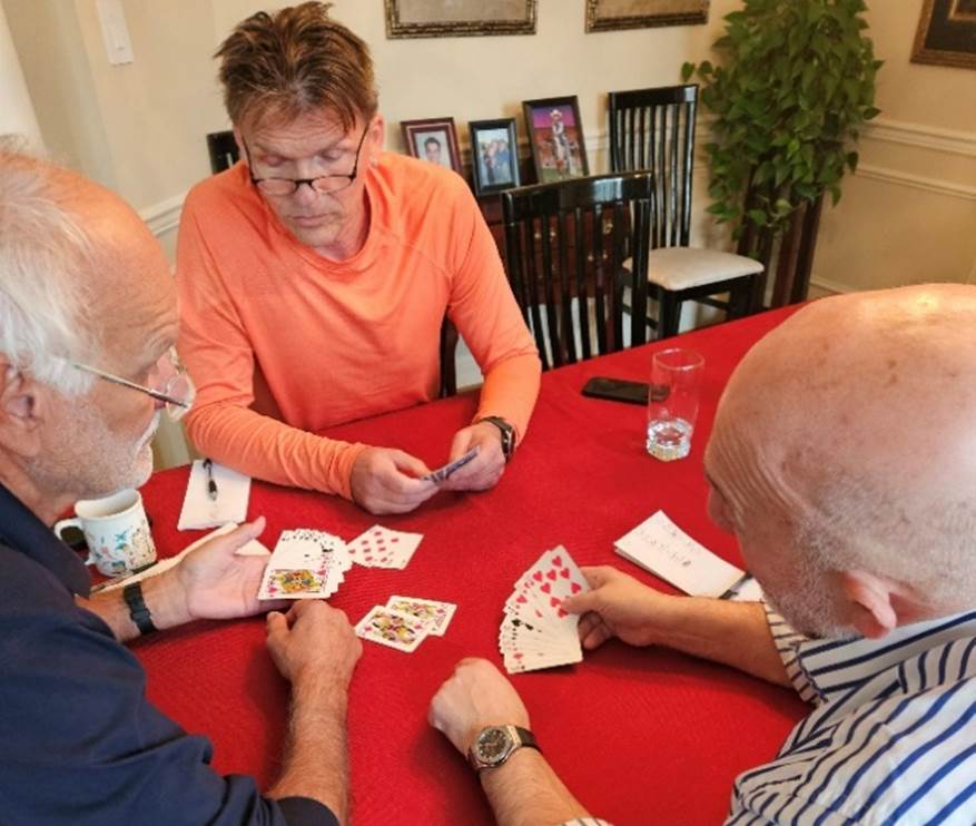 A group of people playing cards

Description automatically generated