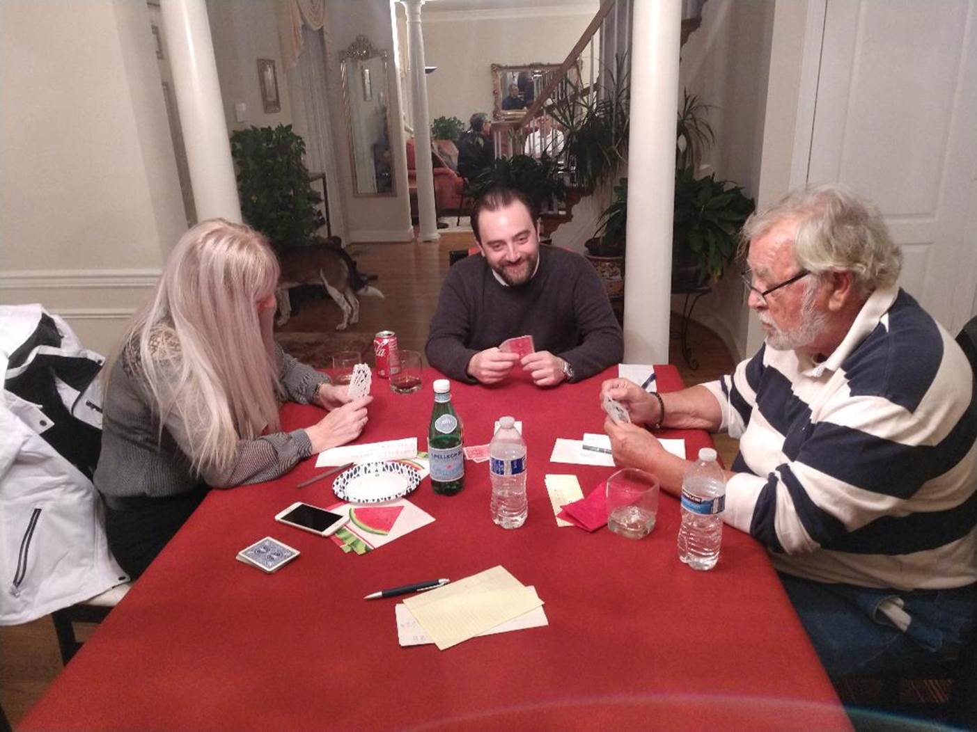 A group of people sitting around a table playing cards

Description automatically generated